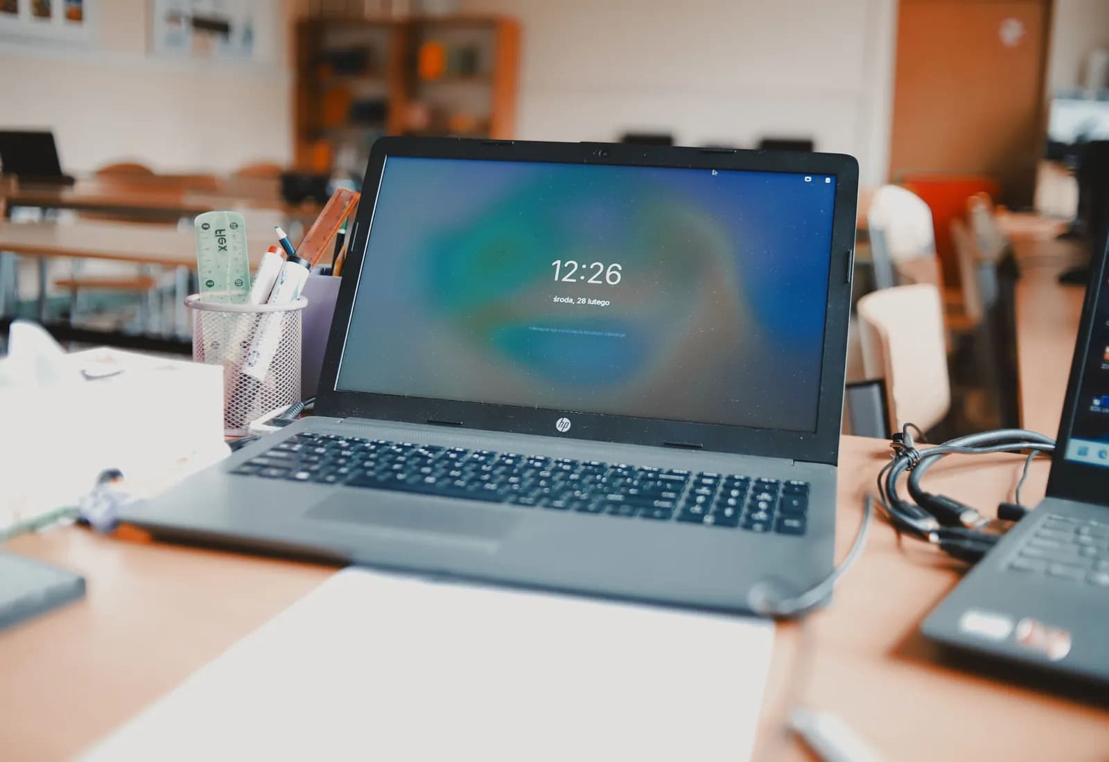 En åben bærbar computer på et bord i et klasselokale, flere borde og maskiner ude af fokus bagved